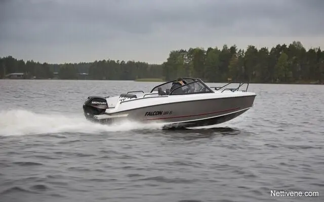 A Falcon 600 G boat speeds across a lake, creating a spray of water, surrounded by green trees and cloudy skies.